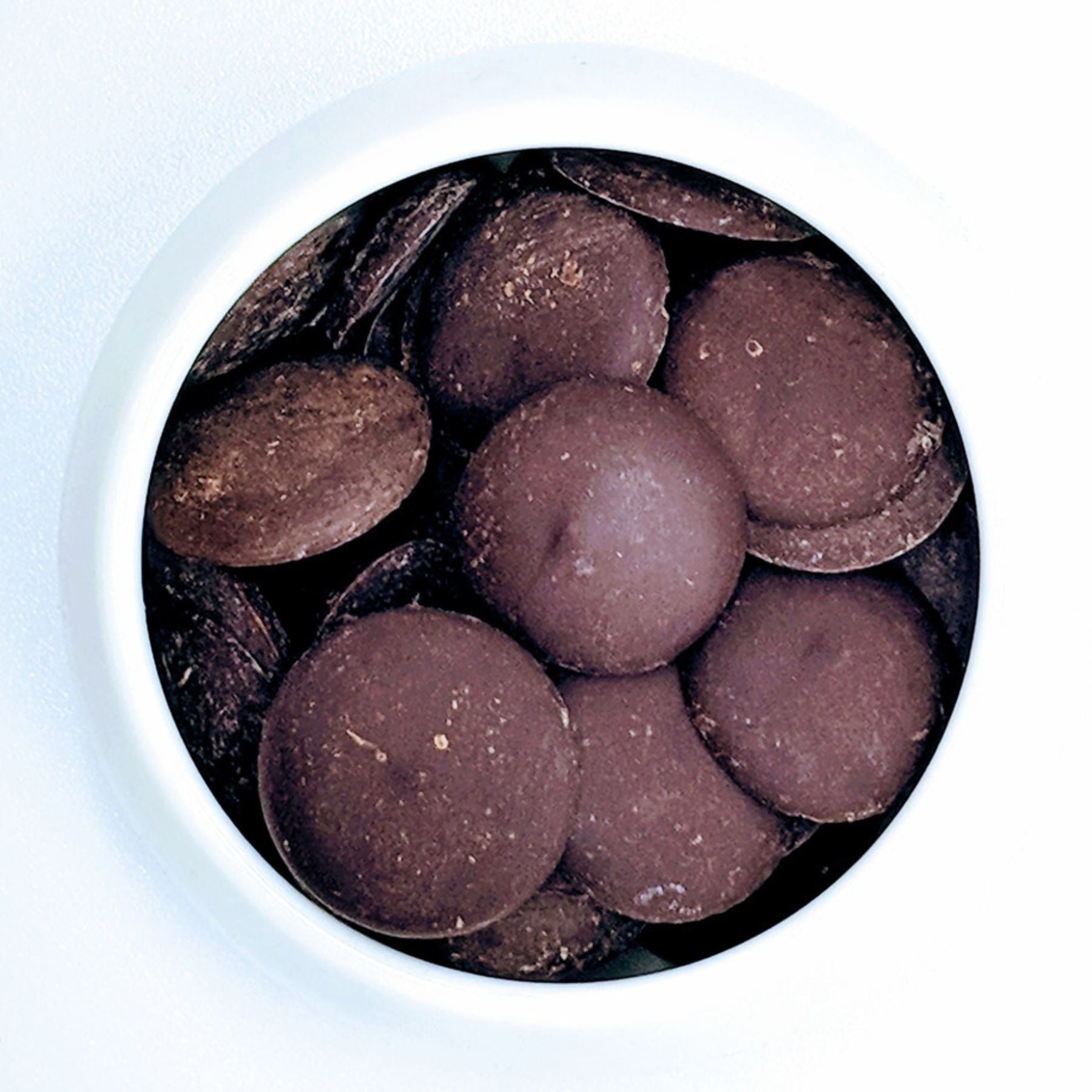 Cocoa Supply Ecuador Single-Origin Made Direct Trade Dark Milk Chocolate Couverture drops in a white bowl on a white background.